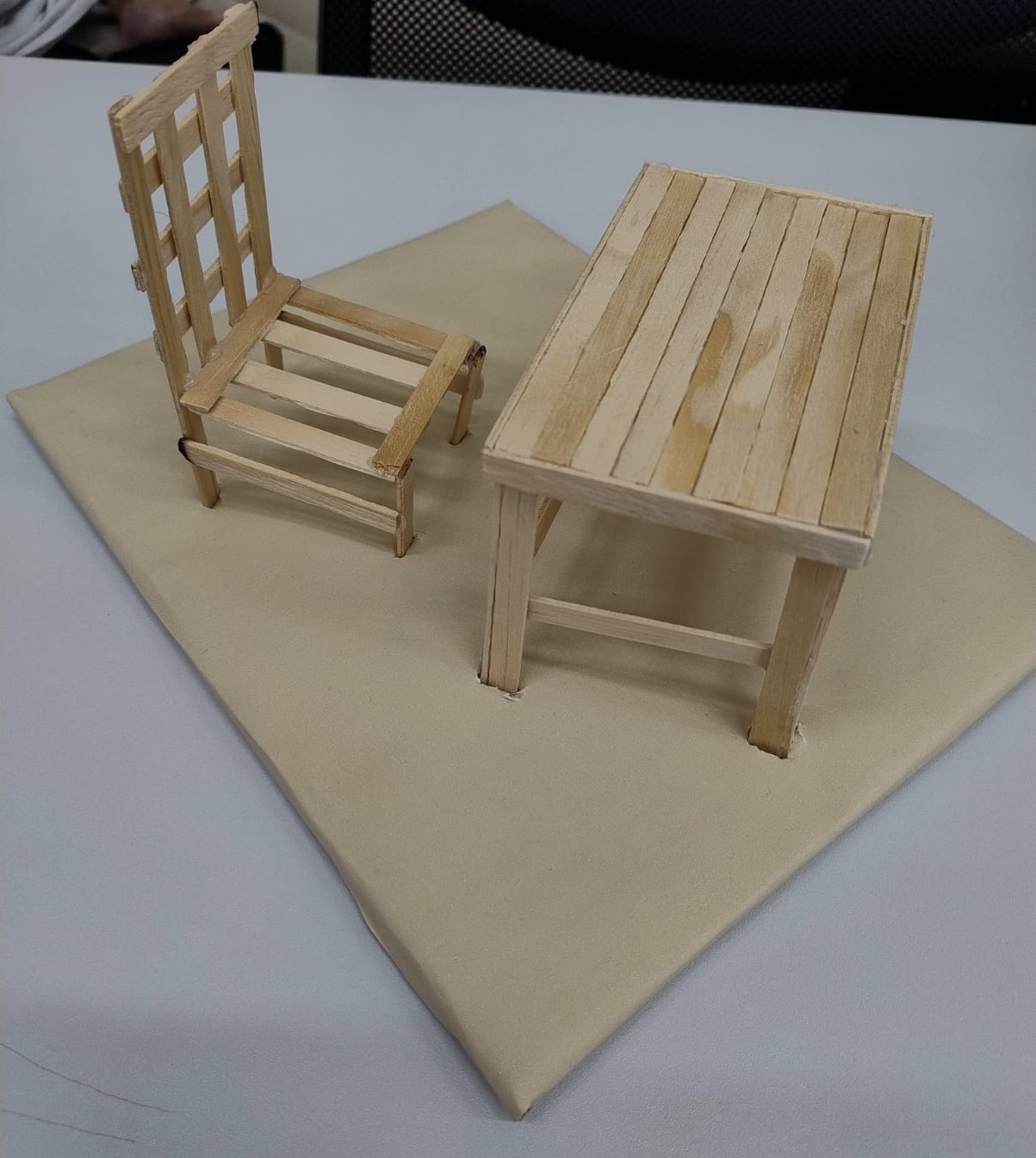  Maquete de mesa e cadeira em miniatura feitas de palitos de madeira, com tampo retangular e pernas simples