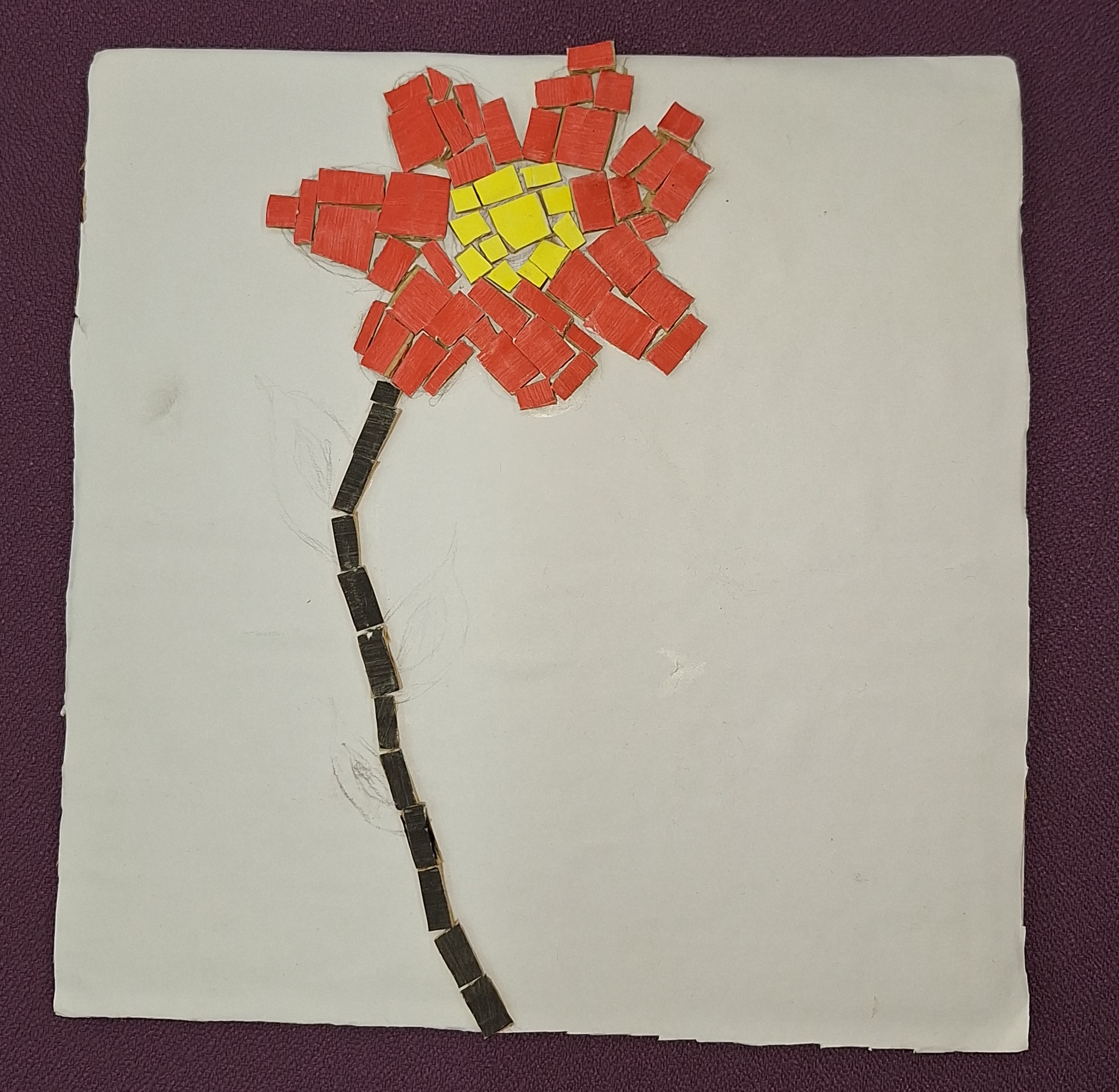 Tela de papelão com flor feita de pedaços pintados, cabo preto, flor vermelha e centro amarelo